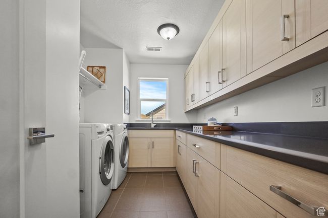 Laundry room with washer and dryer, dark tile patterned floors, a textured ceiling, and cabinet space | Image 25