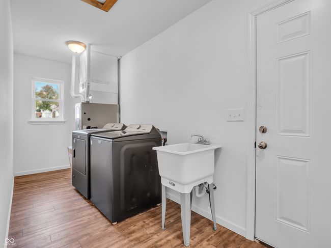 laundry area with light wood-type flooring, washer and clothes dryer, laundry area, and baseboards | Image 20