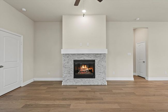 Unfurnished living room featuring ceiling fan, and a stone fireplace. | Image 9