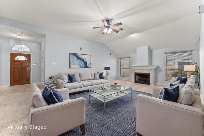 Photo virtually staged. Carpeted living room featuring baseboards, ceiling fan, a wealth of natural light, and vaulted ceiling | Image 7