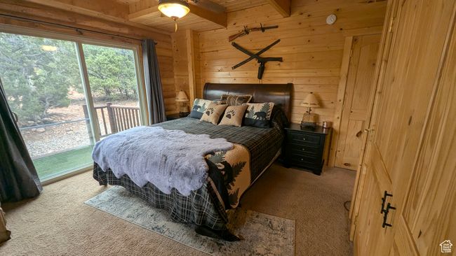 Carpeted bedroom featuring wooden walls, beam ceiling, access to outside, and wood ceiling | Image 18