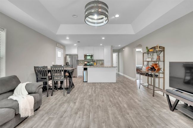 Living room featuring baseboards, recessed lighting, light wood-style flooring, a raised ceiling, and arched walkways | Image 11