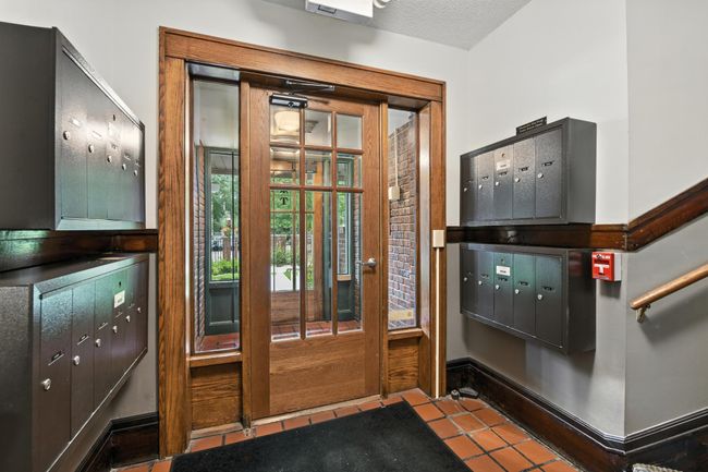 Secure indoor mailboxes in a bright and welcoming entry vestibule with wood-framed glass doors. | Image 4