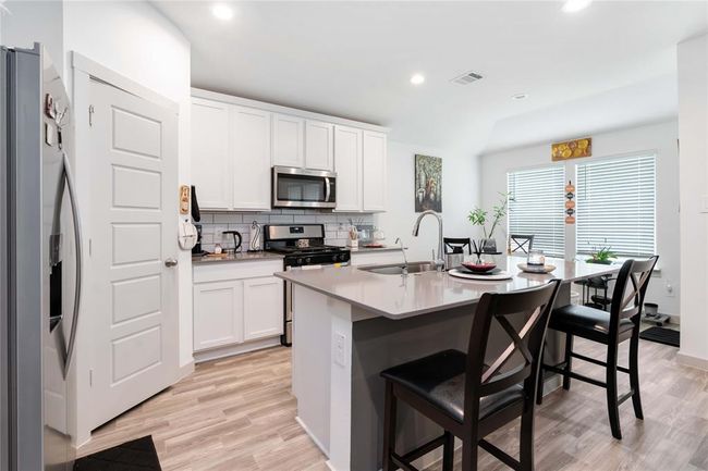 Modern kitchen with stainless steel appliances, sleek countertops, and abundant cabinetry. | Image 7