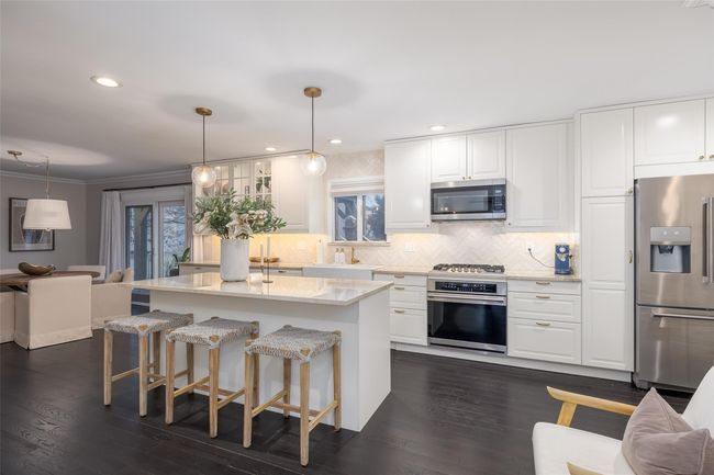 Kitchen with white cabinets, stainless steel appliances, a sink, dark wood-style flooring, and backsplash | Image 18