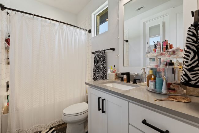 Full bathroom with vanity, visible vents, shower / bath combination with curtain, toilet, and a wealth of natural light | Image 26