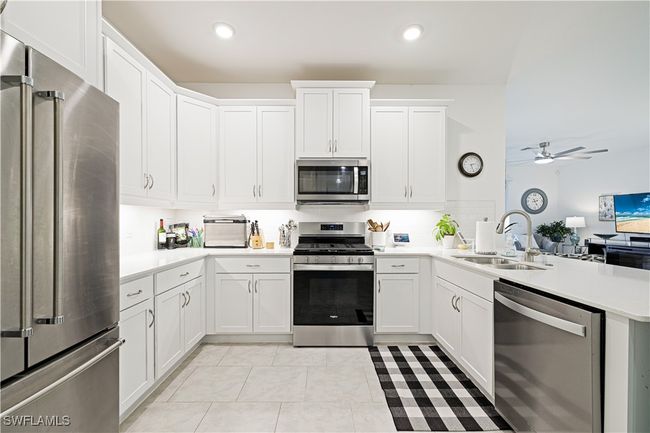 Kitchen featuring stainless steel appliances, a peninsula, light countertops, ceiling fan, and white cabinetry | Image 13