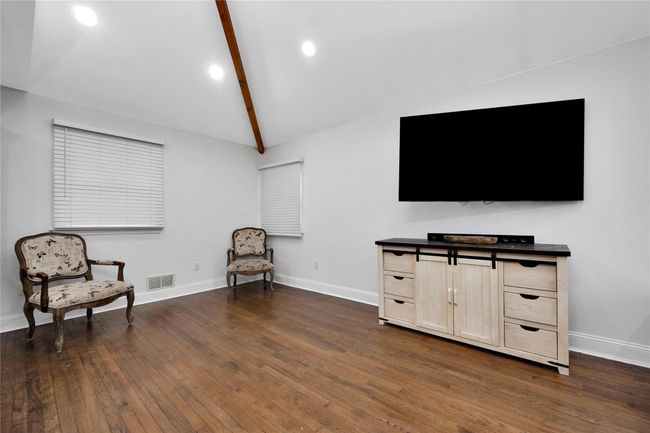Living area with dark wood-style flooring, visible vents, baseboards, and lofted ceiling with beams | Image 8