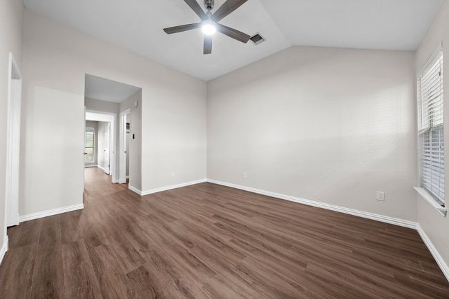 Empty room featuring a ceiling fan, dark wood-style flooring, baseboards, and lofted ceiling | Image 21