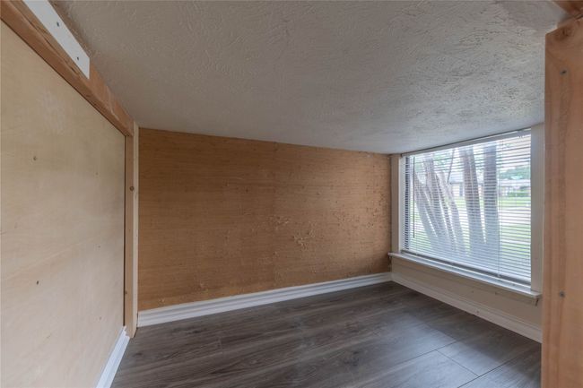 Unfurnished room featuring a textured ceiling, baseboards, and wood finished floors | Image 9