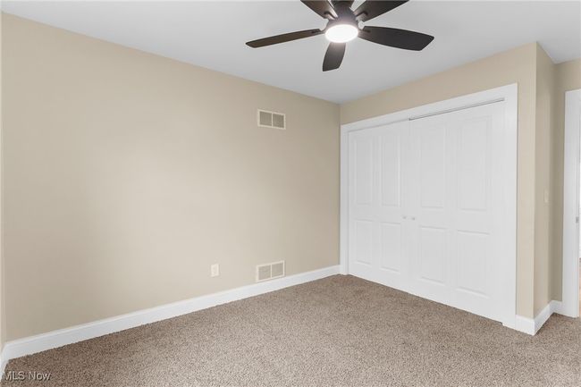 Unfurnished bedroom featuring light carpet, a closet, and a ceiling fan | Image 16