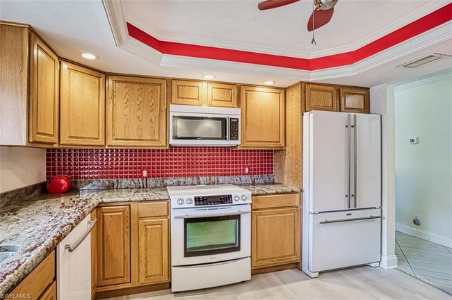 Kitchen featuring stainless steel microwave, a raised ceiling, visible vents, freestanding refrigerator, and electric range | Image 23