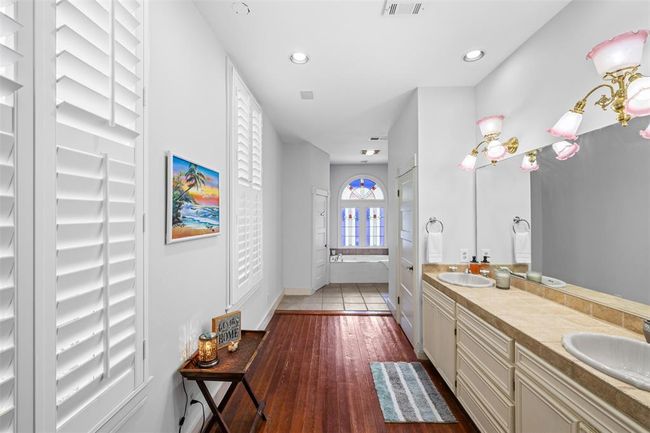 Primary ensuite featuring dual vanities, ample wardrobe space, a soothing jetted tub, a separate shower, and a discreet private toilet. | Image 16