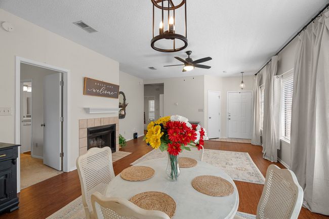 Dining room featuring wood finished floors, a ceiling fan, a fireplace, and a textured ceiling | Image 8