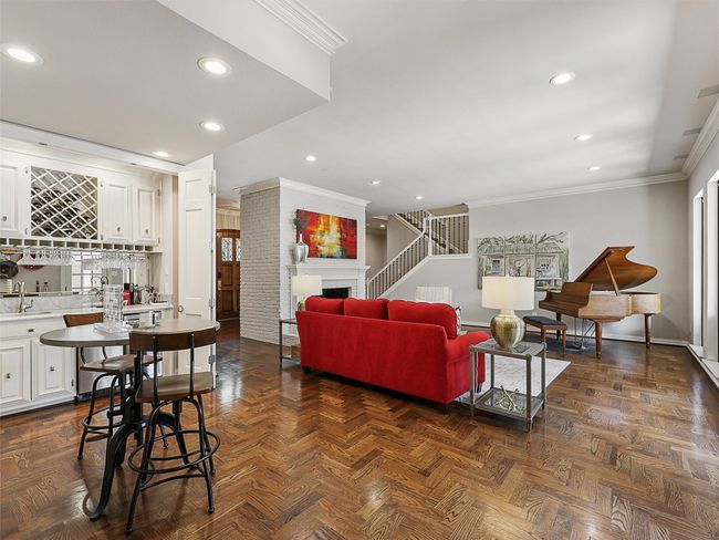 Living area featuring ornamental molding, wet bar, recessed lighting, stairway, and a fireplace | Image 11