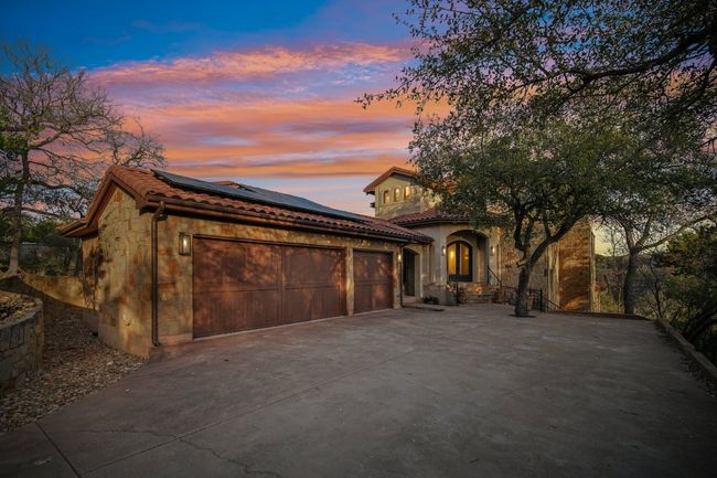 View of front of property featuring stone siding, solar panels, an attached garage, and a tile roof | Image 4
