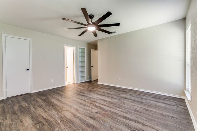 Empty room with a ceiling fan, wood finished floors, and built in shelves | Image 21