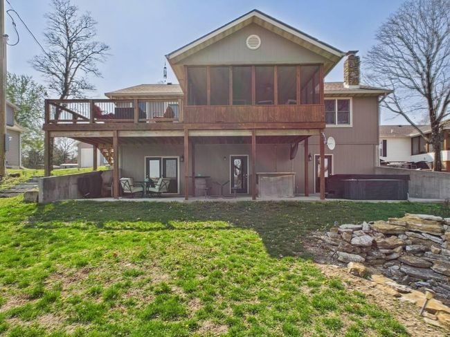 Rear view of house with a chimney, a patio area, a hot tub, a yard, and a sunroom | Image 6