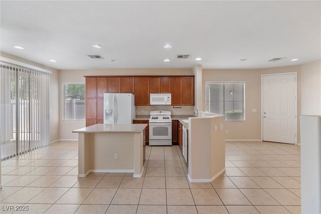 Kitchen featuring white appliances, light tile patterned floors, light countertops, a kitchen island, and recessed lighting | Image 5