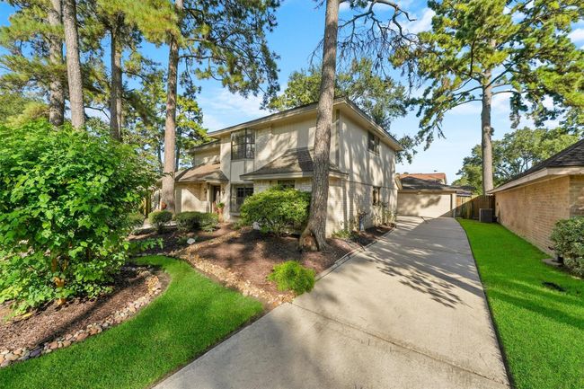 This picturesque home features a classic two-story design with a well-maintained exterior. It's nestled among mature trees with lush landscaping and a long driveway leading to a detached garage. The property offers a serene, inviting atmosphere perfect for families. | Image 9