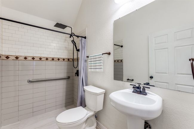 Bathroom featuring a tile shower with rain shower head and lofted ceiling | Image 18