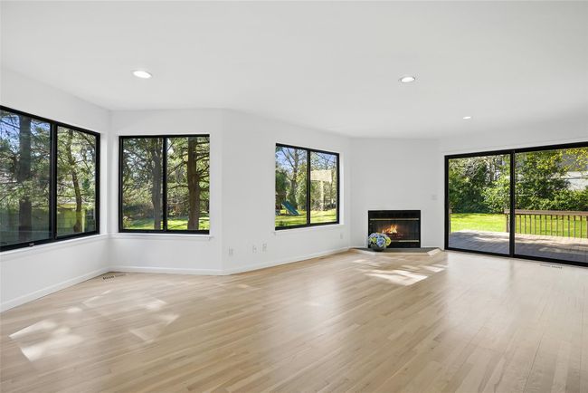 An additional view showcases multiple windows, fireplace and sliding glass doors to the deck. | Image 6
