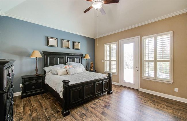 Primary bedroom with wood tile flooring. Door leads to the covered back patio. | Image 30