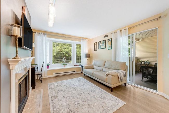 Living area featuring a baseboard radiator, light wood-style floors, a fireplace, and baseboards | Image 12