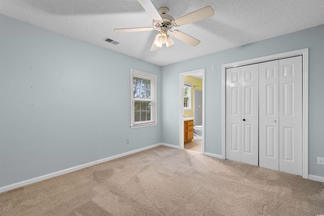 Unfurnished bedroom featuring carpet floors, a textured ceiling, a closet, ensuite bathroom, and a ceiling fan | Image 14