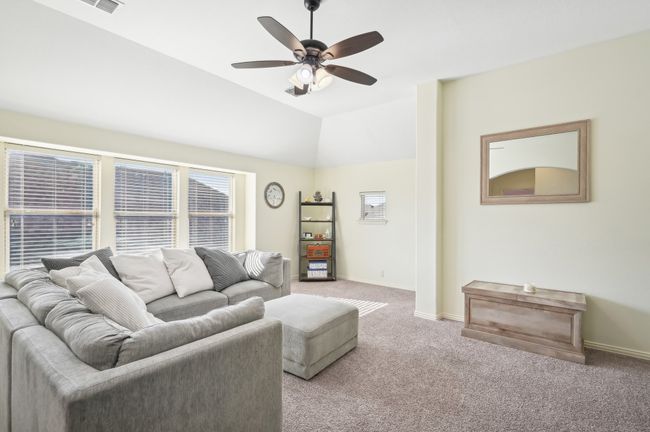Living room with light carpet, baseboards, a ceiling fan, and vaulted ceiling | Image 26