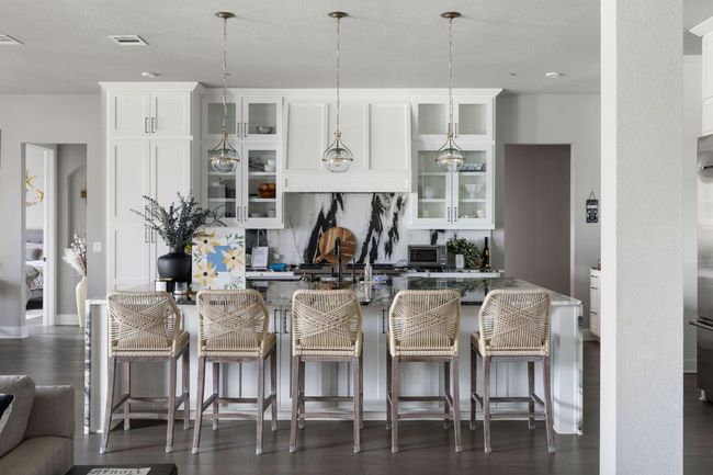 Kitchen featuring visible vents, an island with sink, hanging light fixtures, and a breakfast bar area | Image 6