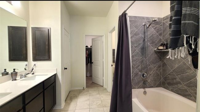 Full bathroom with shower / bath combo with shower curtain, double vanity, tile patterned floors, and a spacious closet | Image 21