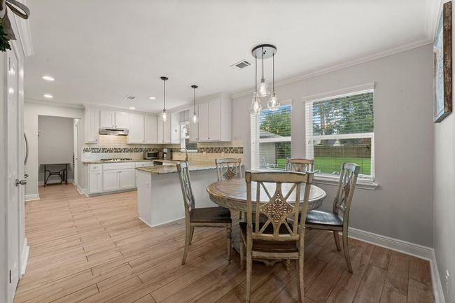 This photo showcases a bright, open-concept kitchen and dining area. It features large windows offering a view of the backyard. | Image 9