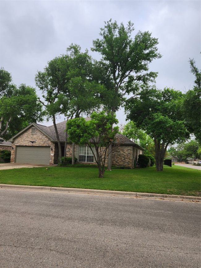 View of front of house with stone siding, a front yard, an attached garage, and driveway | Image 4