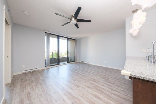 Unfurnished living room with a baseboard radiator, a ceiling fan, floor to ceiling windows, and light wood-style floors | Image 10
