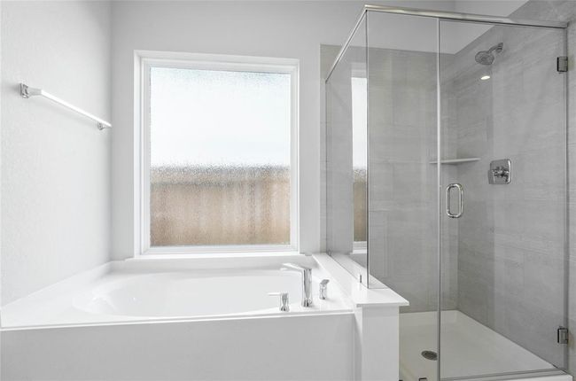 Additional view of the primary bathroom which features a large walk-in shower with tile surround, large garden tub to soak after a long hard day, and a rain glass window allowing in the natural light. | Image 12