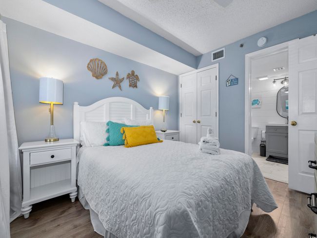Bedroom featuring visible vents, a textured ceiling, wood finished floors, connected bathroom, and a closet | Image 16