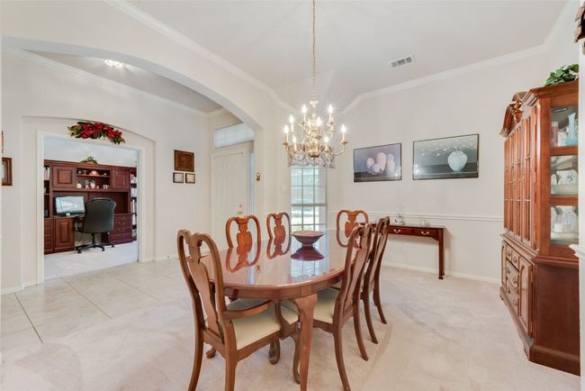 Dining area featuring arched walkways, a chandelier, crown molding, an office area, and light carpet | Image 17