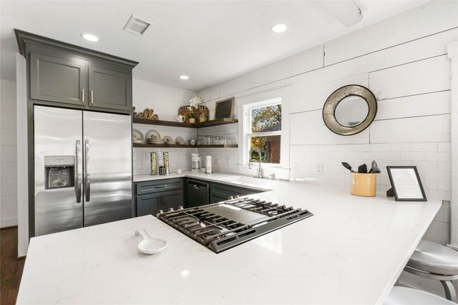 Kitchen featuring stainless steel appliances, open shelves, light stone countertops, tasteful backsplash, and recessed lighting | Image 11