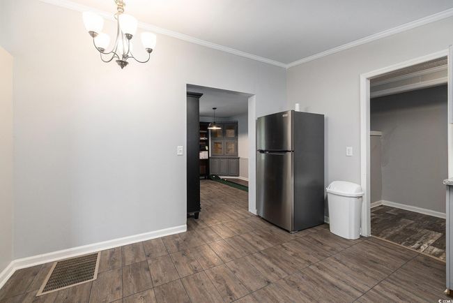 Unfurnished dining area featuring crown molding, a chandelier, and wood finished floors | Image 12
