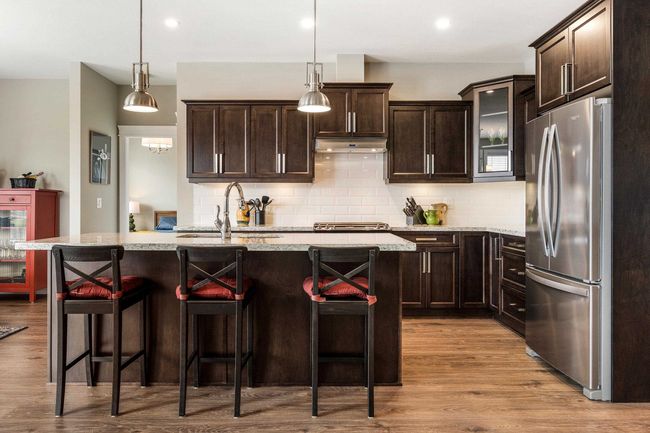 Kitchen with decorative backsplash, wood finished floors, under cabinet range hood, a sink, and freestanding refrigerator | Image 14