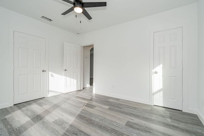Unfurnished bedroom with arched walkways, wood finished floors, a ceiling fan, visible vents, and baseboards | Image 15