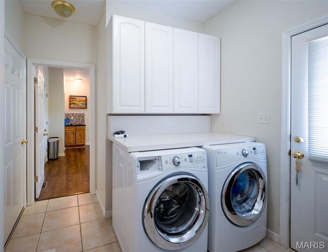 Washroom with cabinet space, separate washer and dryer, and light tile patterned floors | Image 19