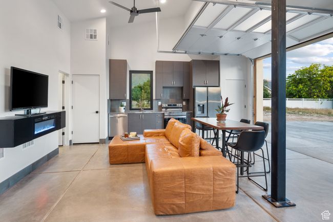 Living room featuring a towering ceiling, finished concrete flooring, a ceiling fan, healthy amount of natural light, and recessed lighting | Image 75