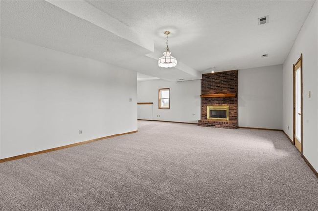 Unfurnished living room with a fireplace, carpet, and a textured ceiling | Image 24