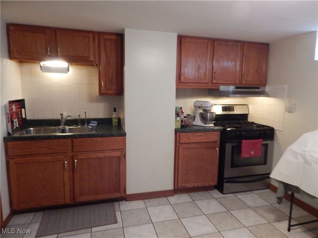 Basement summer Kitchen with under cabinet range hood, a sink, backsplash, dark countertops, gas range & Ceramic Flooring. So handy for holidays, entertaining & parties. | Image 25