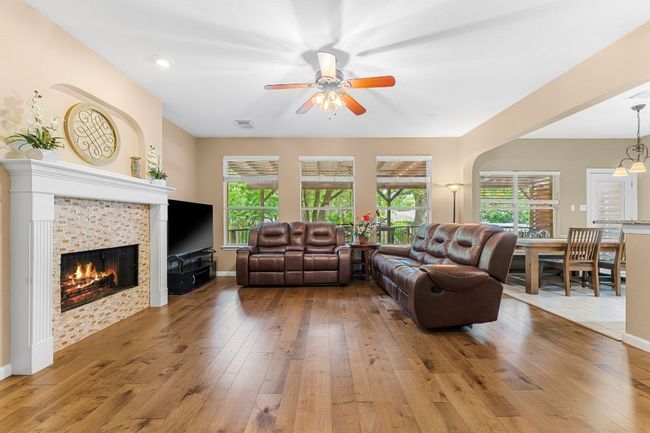 Living room featuring hardwood / wood-style flooring, healthy amount of natural light, a ceiling fan, and a fireplace | Image 6