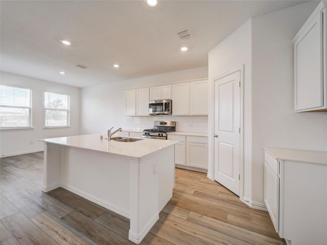 Kitchen with stainless steel appliances, a sink, tasteful backsplash, light wood-style floors, and white cabinets | Image 13