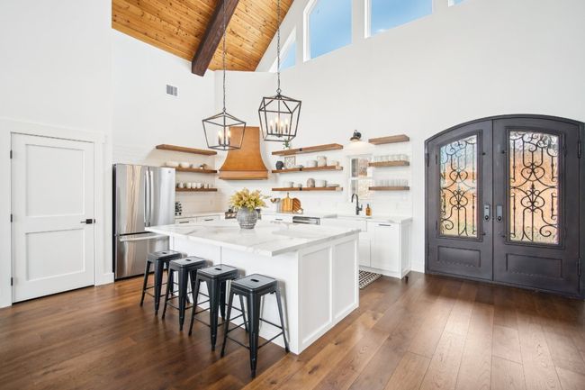 Kitchen with freestanding refrigerator, open shelves, high vaulted ceiling, premium range hood, and french doors | Image 5