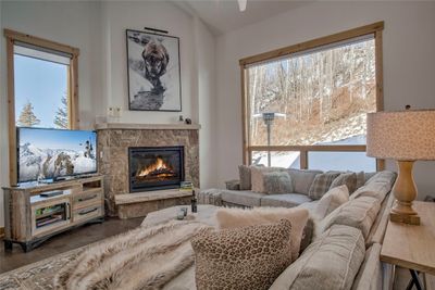 Living room featuring dark hardwood / wood-style floors, a stone fireplace, and lofted ceiling | Image 1